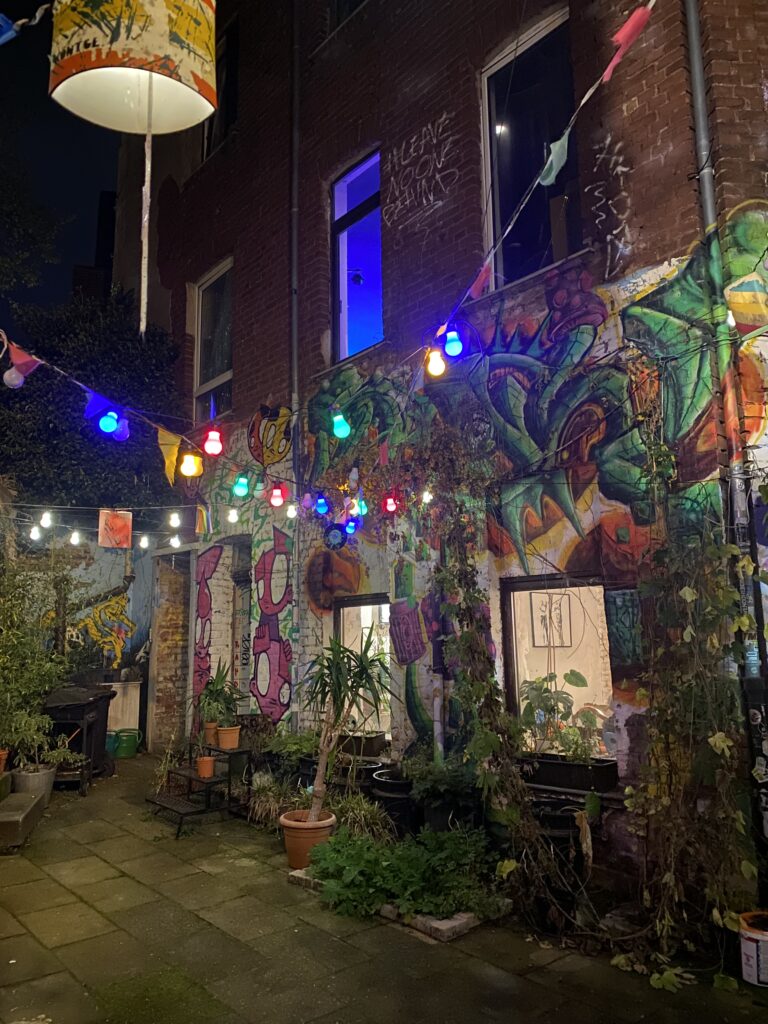 Auf dem Bild ist ein beleuchteter Innenhof zu sehen. In der Luft hängen bunte Lichterketten.